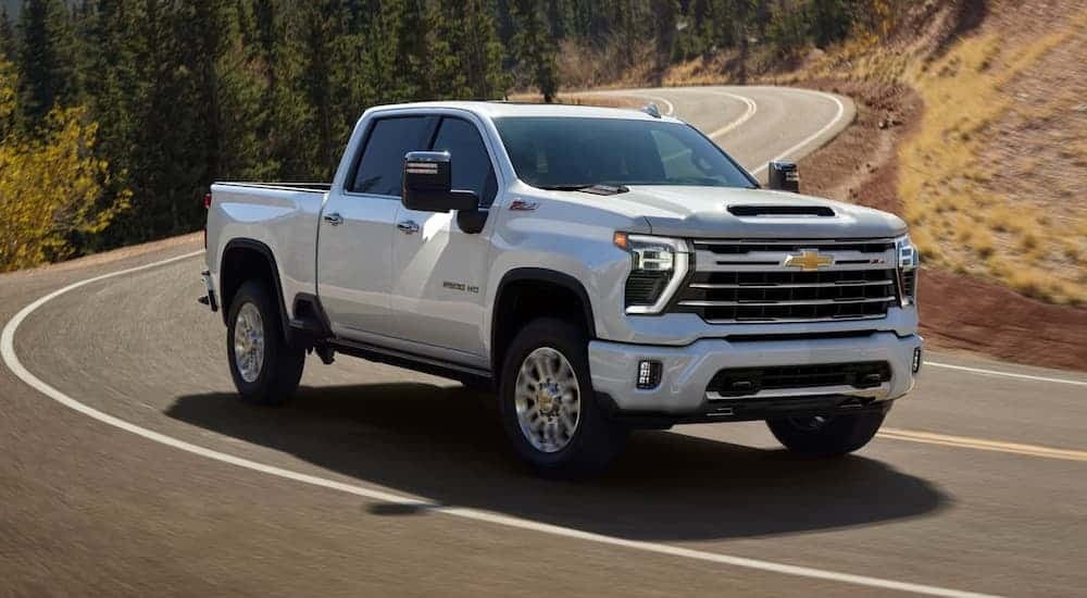 A white 2025 Chevy Silverado 2500 driving down a back road.