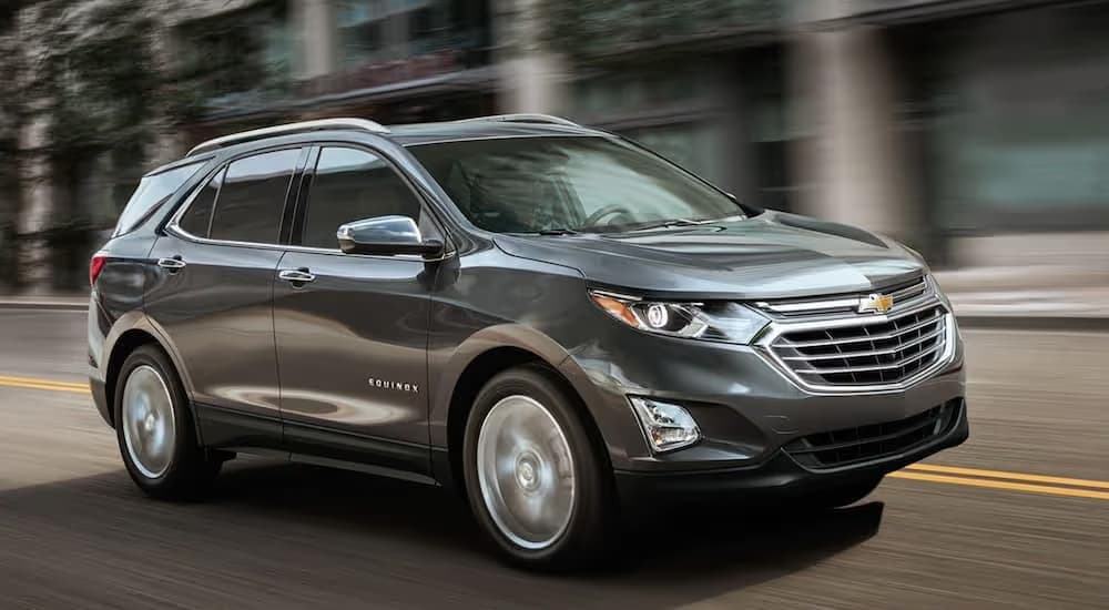 A grey 2019 Chevy Equinox is shown driving through a city after leaving a used Chevy dealership.