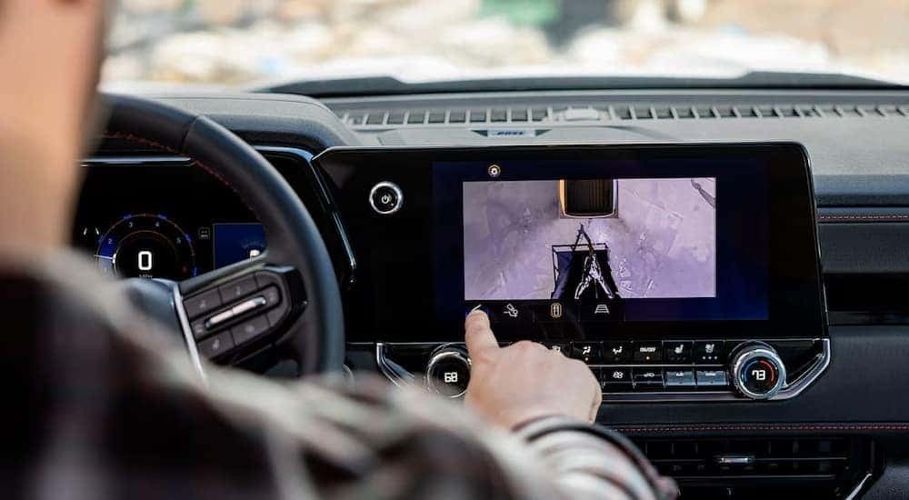A man is using the backup camera in a 2024 Chevy Colorado truck for sale.