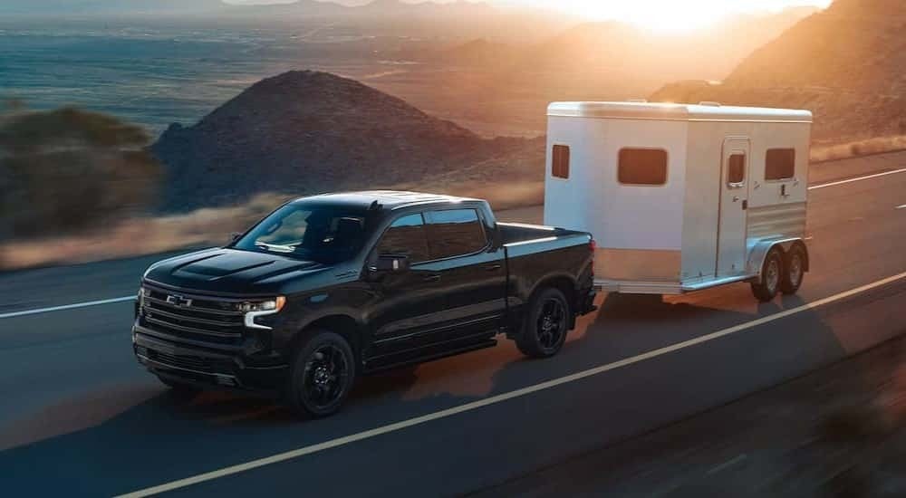 A black 2025 Chevy Silverado 1500 High Country towing a trailer.