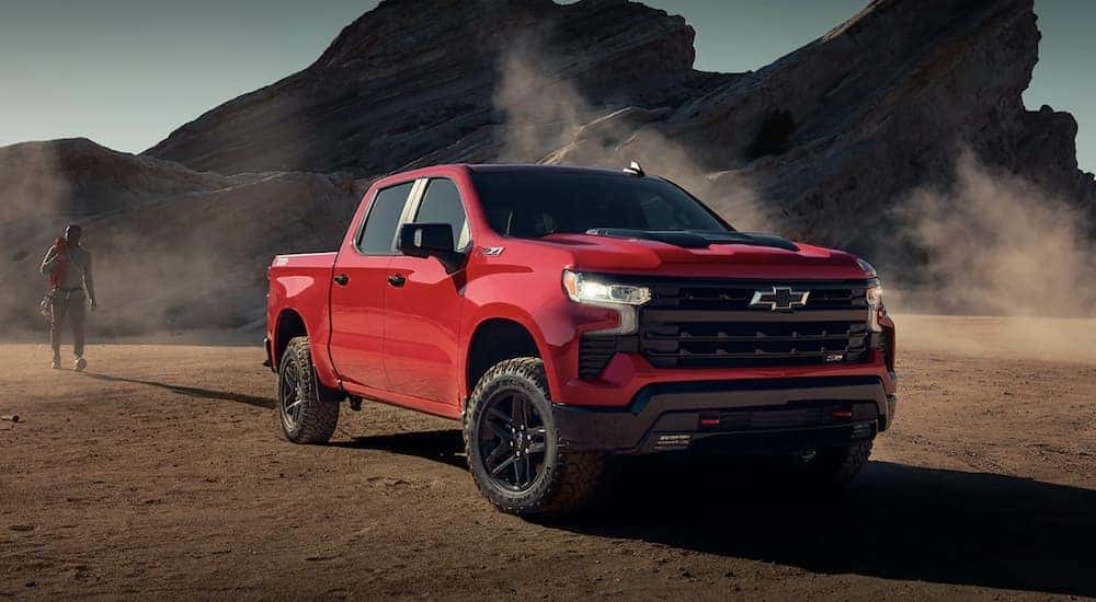 A red 2023 Chevy Colorado Trail Boss is shown driving on a dirt road.