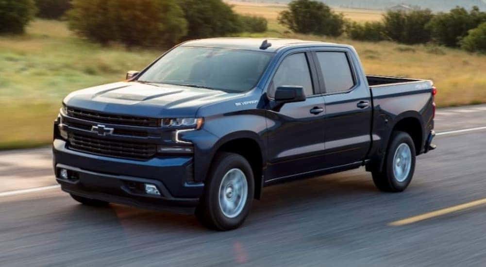 A popular used Chevy Silverado for sale, a black 2021 Chevy Silverado 1500 LT, is shown driving on a highway.