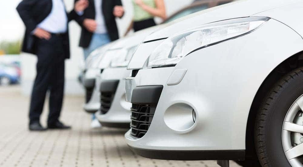 A row of white cars are shown parked at a car dealer.