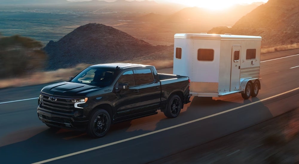 Black 2026 Chevy Silverado 1500 High Country towing a trailer