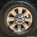 Close-up of a shiny chrome car wheel with six spokes, fitted with a black Michelin tire. The image conveys a clean, polished, and sturdy appearance.