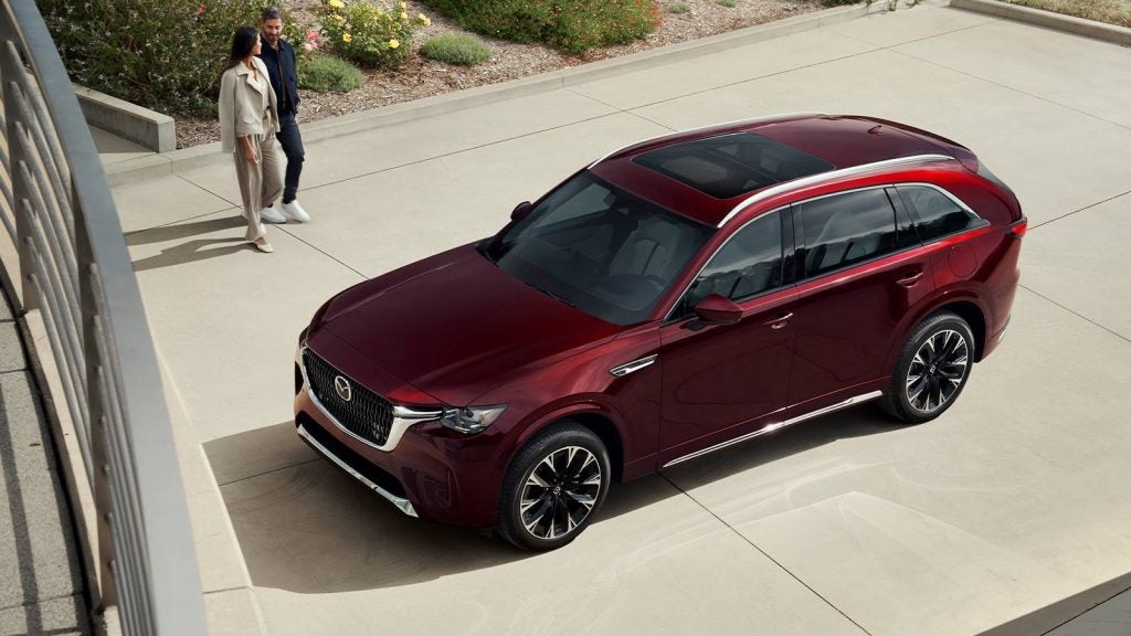 Couple walking toward a red Mazda SUV parked outdoors, viewed from above.