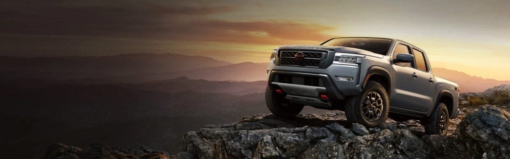 Nissan pickup truck parked on a rocky mountain at sunset