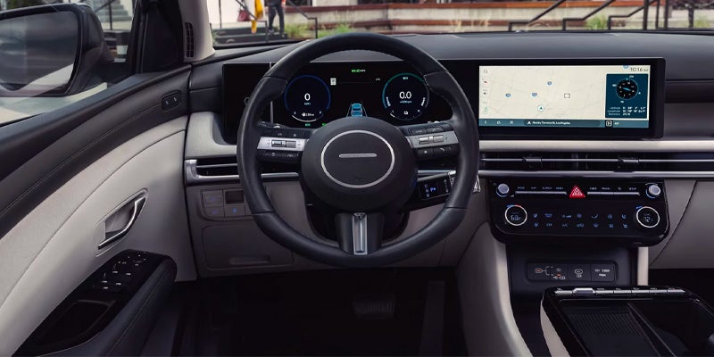 Interior view of a Hyundai car, showcasing the steering wheel and dashboard with digital displays and controls.