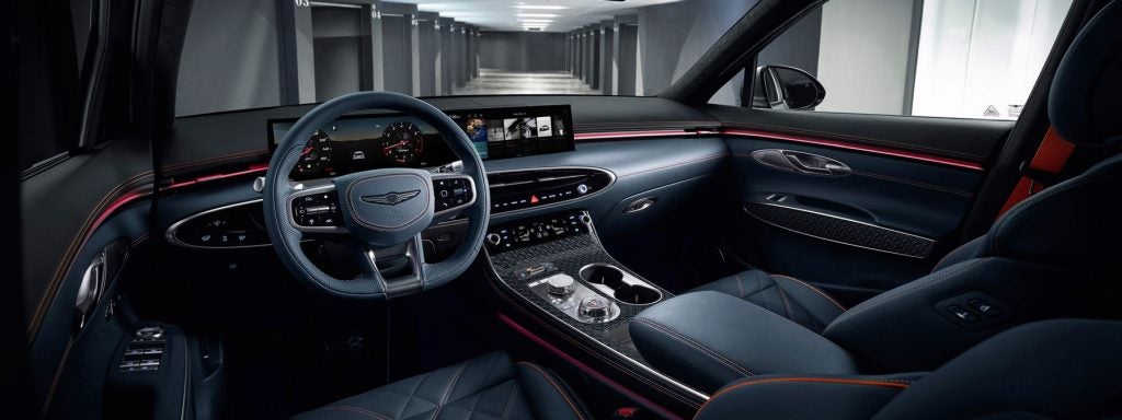Interior of a Genesis luxury car, showcasing a modern dashboard, steering wheel, and seating with detailed stitching and high-tech display screens.