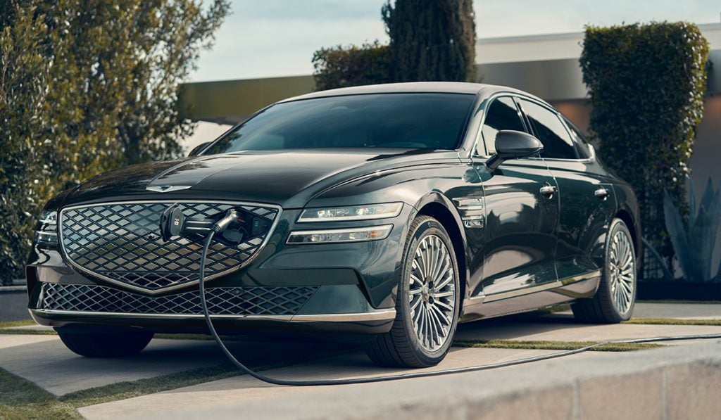 A sleek, Genesis Electric car parked against a modern cityscape, showcasing its luxury design