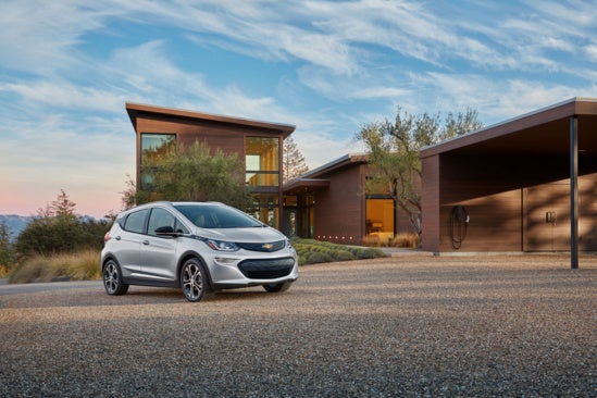 Chevy EV parked in front of a model home in the desert at dusk
