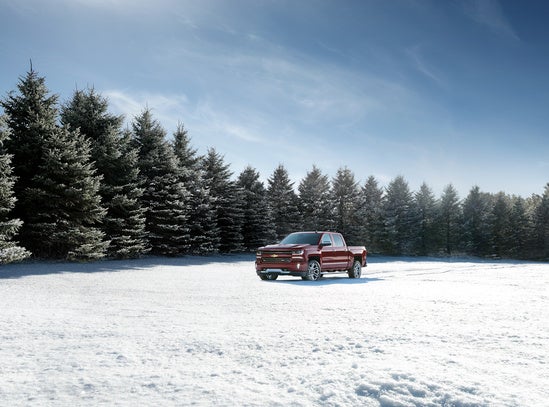 red Chevy Silverado parked in snowy pasture in the winter