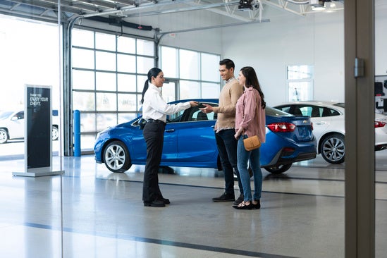 customers with a sales rep in the garage of a Chevy dealership