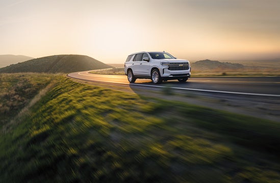 white Chevy Tahoe driving on a rural road at sunset