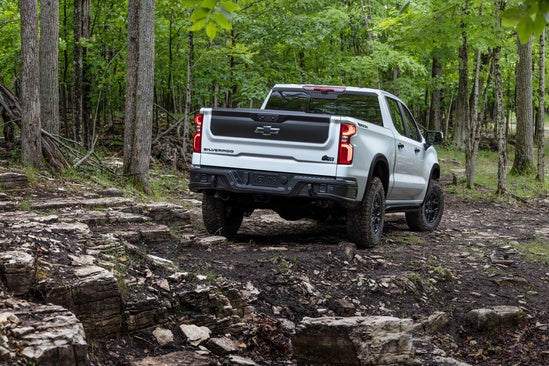 white Chevy Silverado driving off road in the woods