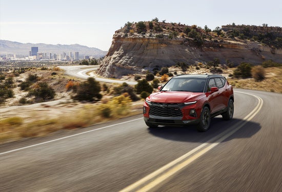 red Chevy Blazer driving on a rural desert road