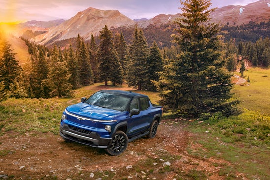 blue Chevy Silverado HD parked on a remote hillside in the mountains