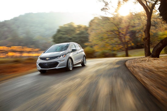 Chevy Bolt driving down a rural road at sunset in autumn