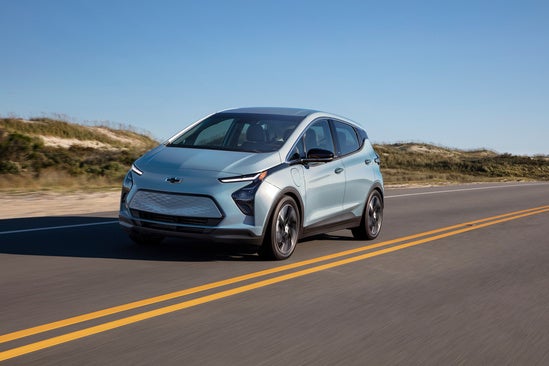 light blue Chevy EV driving along the coast
