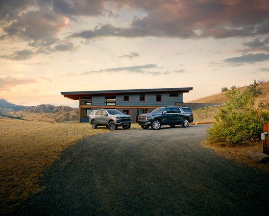 two dark colored Chevy Tahoe's parked in front of a modern building in the rural desert