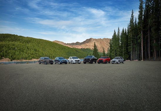 collection of Chevy SUVs parked in front of lakes with mountains in the background