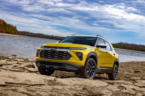 yellow Chevy Trailblazer parked off road in front of a lake