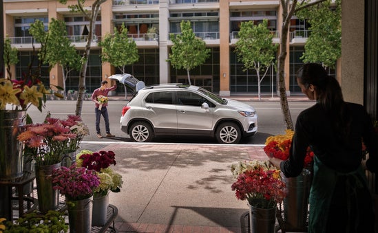 man closing the hatchback of his Chevy in front of flower shop