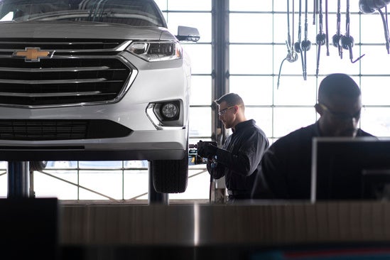 service technician working on the tires of a Chevy in a garage