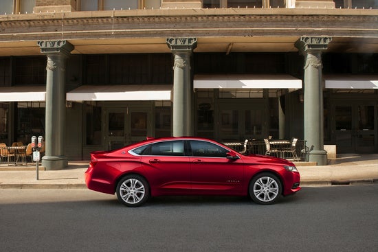 red Chevy sedan parked downtown in front of an historic building