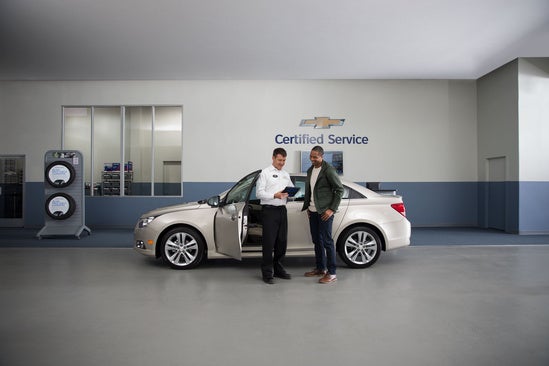 service technician going over paperwork with a customer in the garage of a dealership