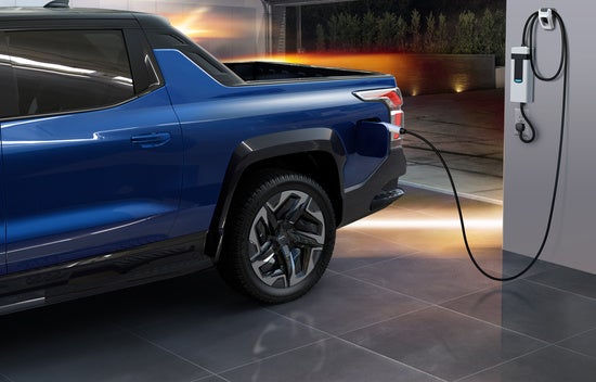 blue Chevy Silverado EV parked in a garage at home charging