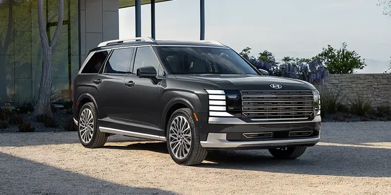 A black Hyundai Hybrid SUV parked outside a modern building with a gravel driveway.