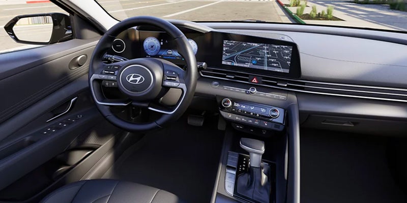 Interior view of a Hyundai car, showcasing the dashboard, steering wheel, infotainment screen, and gear shift.