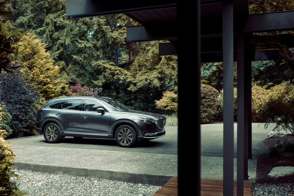 dark green Maxda SUV parked in the driveway of a modern home