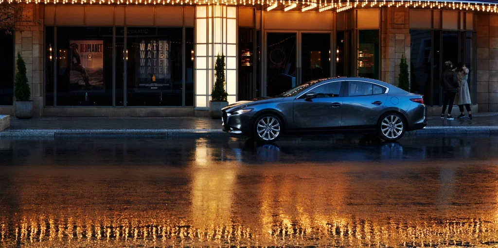 Mazda3 parked outside a bright hotel at night