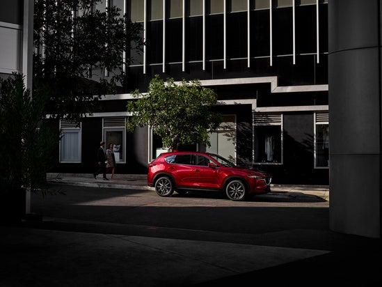 red Mazda CX-5 parked downtown in front of a city building