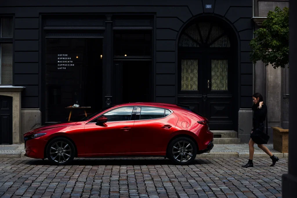 woman walking towards her red Mazda parked downtown on a cobblestone road