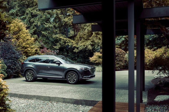 gray Mazda CX-9 parked in the driveway of a modern home