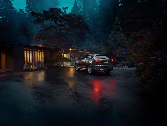 Mazda SUV parked in front of a modern home at night