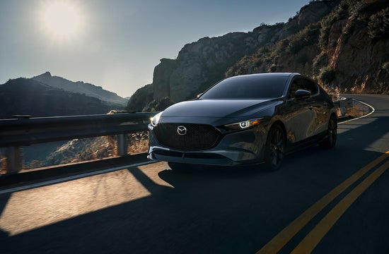 Mazda3 driving on a rural mountain road in the morning sun