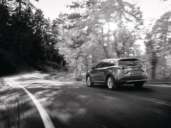 black and white photo of a Mazda SUV driving on a rural road