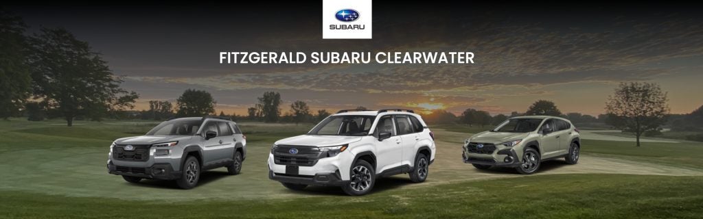 Three Subaru models on display at Fitzgerald Subaru Clearwater with a peaceful golf course setting.