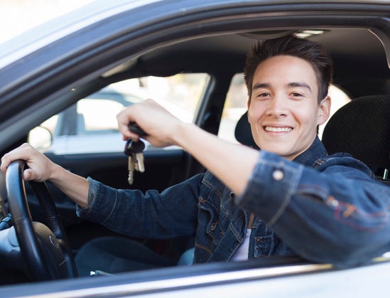 Young male car driver showing new car keys and car.