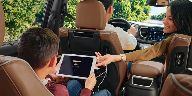 A family inside a 2026 Chrysler Pacifica, with a child using a tablet while sitting in the back seat and parents in the front seats.