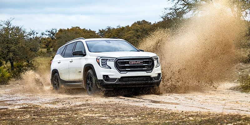 A white 2024 GMC Terrain driving through dirt.