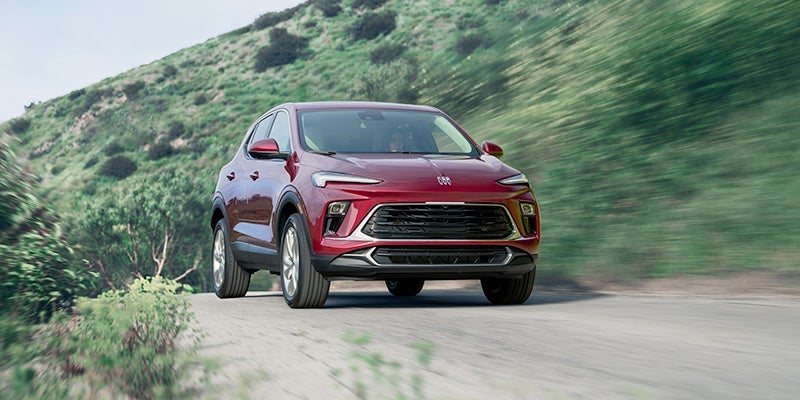 A red 2024 Buick Encore GX driving on a dirt road.