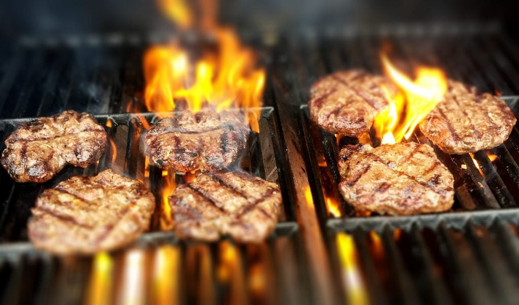 Flaming burgers on a grill.