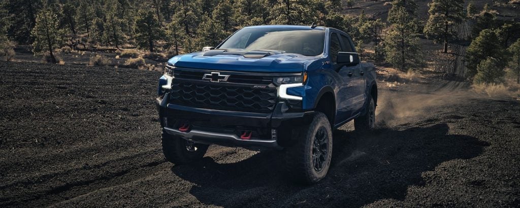 A blue 2022 Chevrolet Silverado driving up a hill.