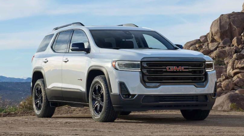 White 2022 GMC Acadia parked in front of some rocks.