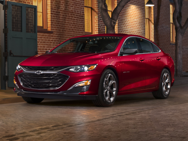 All-New 2024 Radiant Red Tintcoat Chevrolet Malibu parked on a cobblestone street in front of a brick building in Oxford, NC.